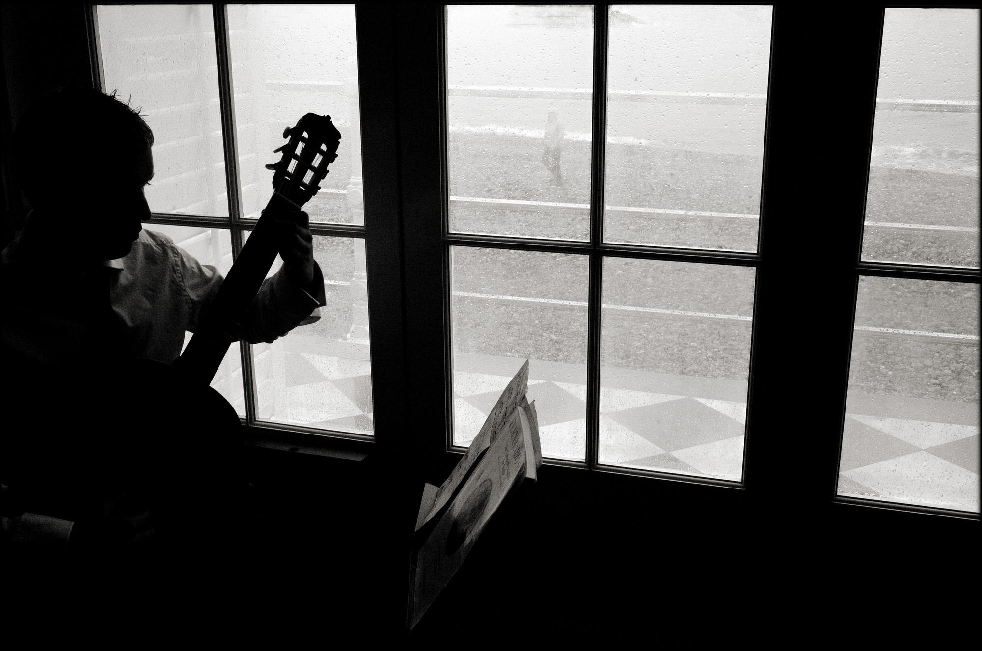 Featured image: Person playing guitar against window-e49c45604ee3dcdcf304