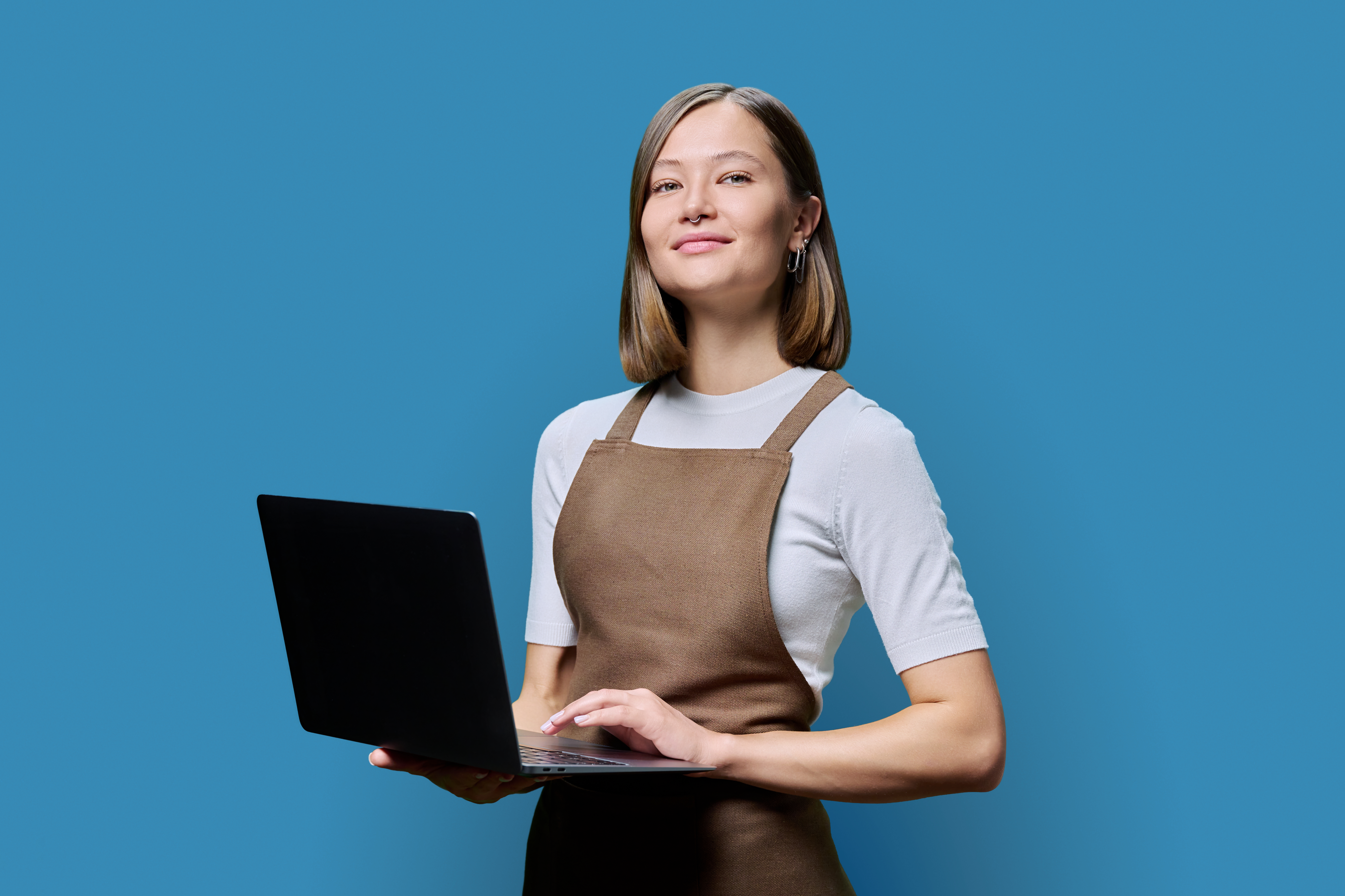 portrait of young woman in apron holding laptop on 1f7145ee226a35e8cf37