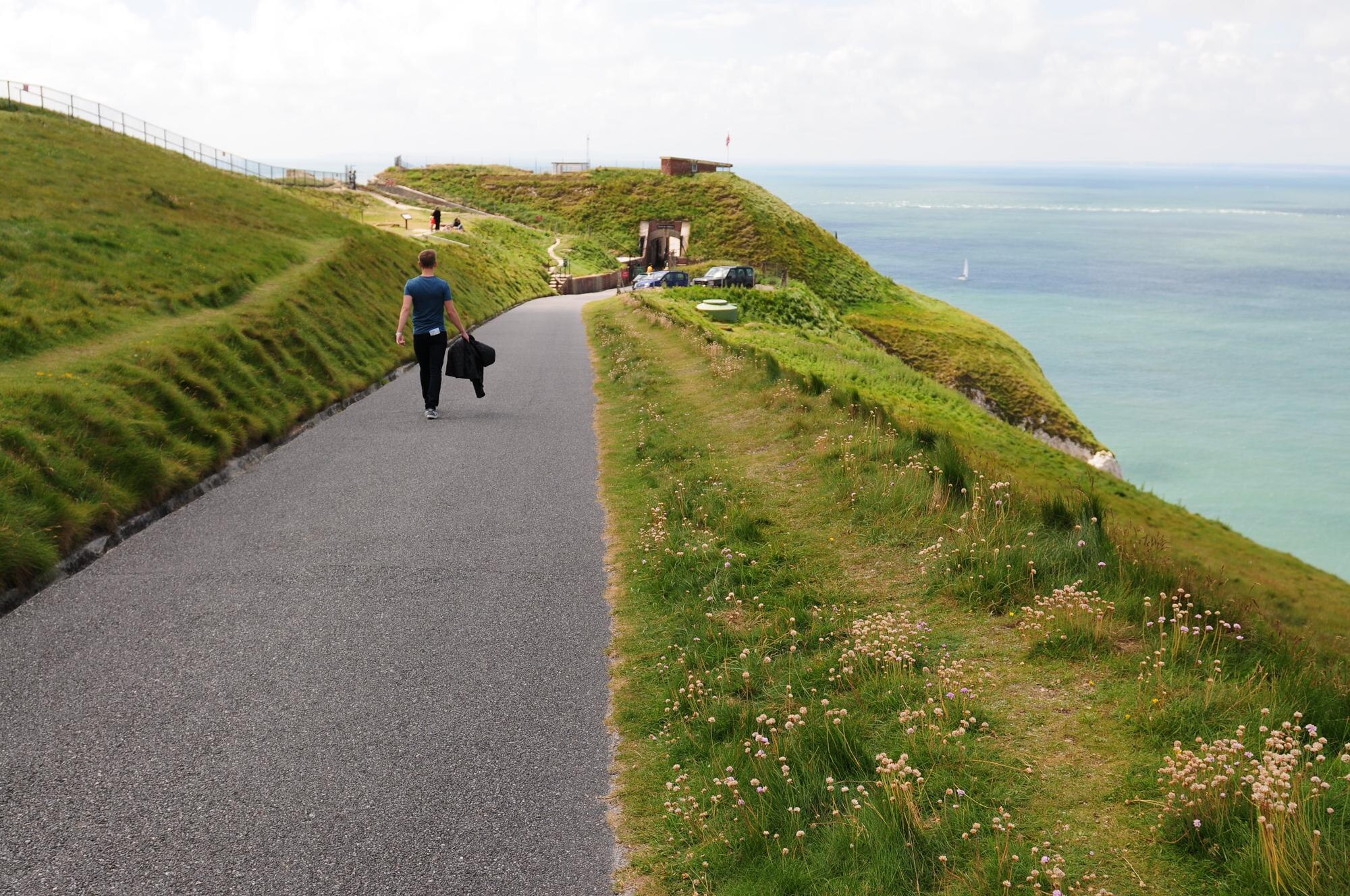 rear view of man walking on road by sea against sk e25b2cae1b4c688f7503 BTOURS