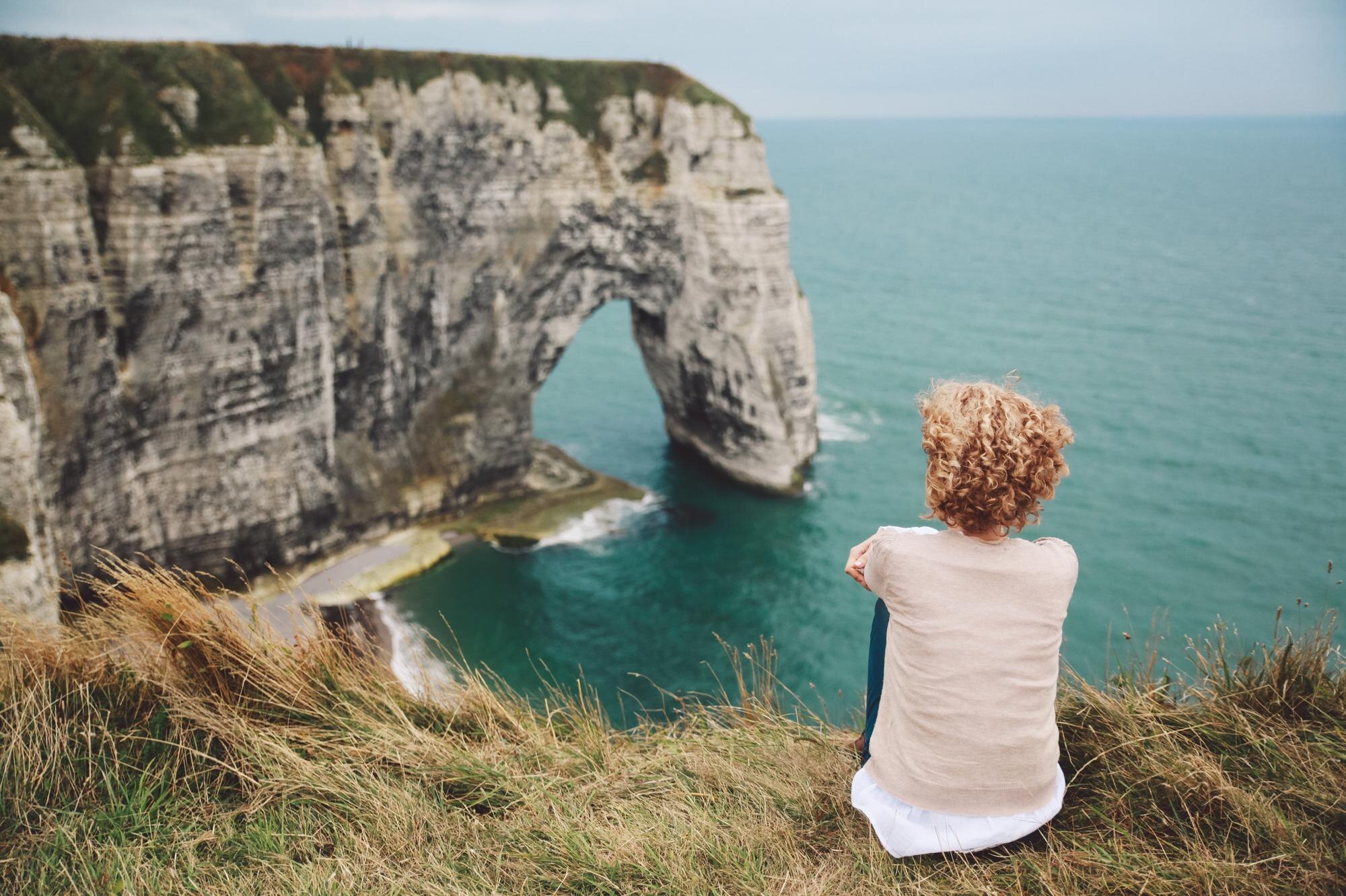 Hidden History, Open Roads: Lesser‑Known UK and Ireland Sites for Your Self‑Drive Itinerary 5 rear view of woman sitting on field by sea against 2ff6a88ea37fdf547e1c BTOURS