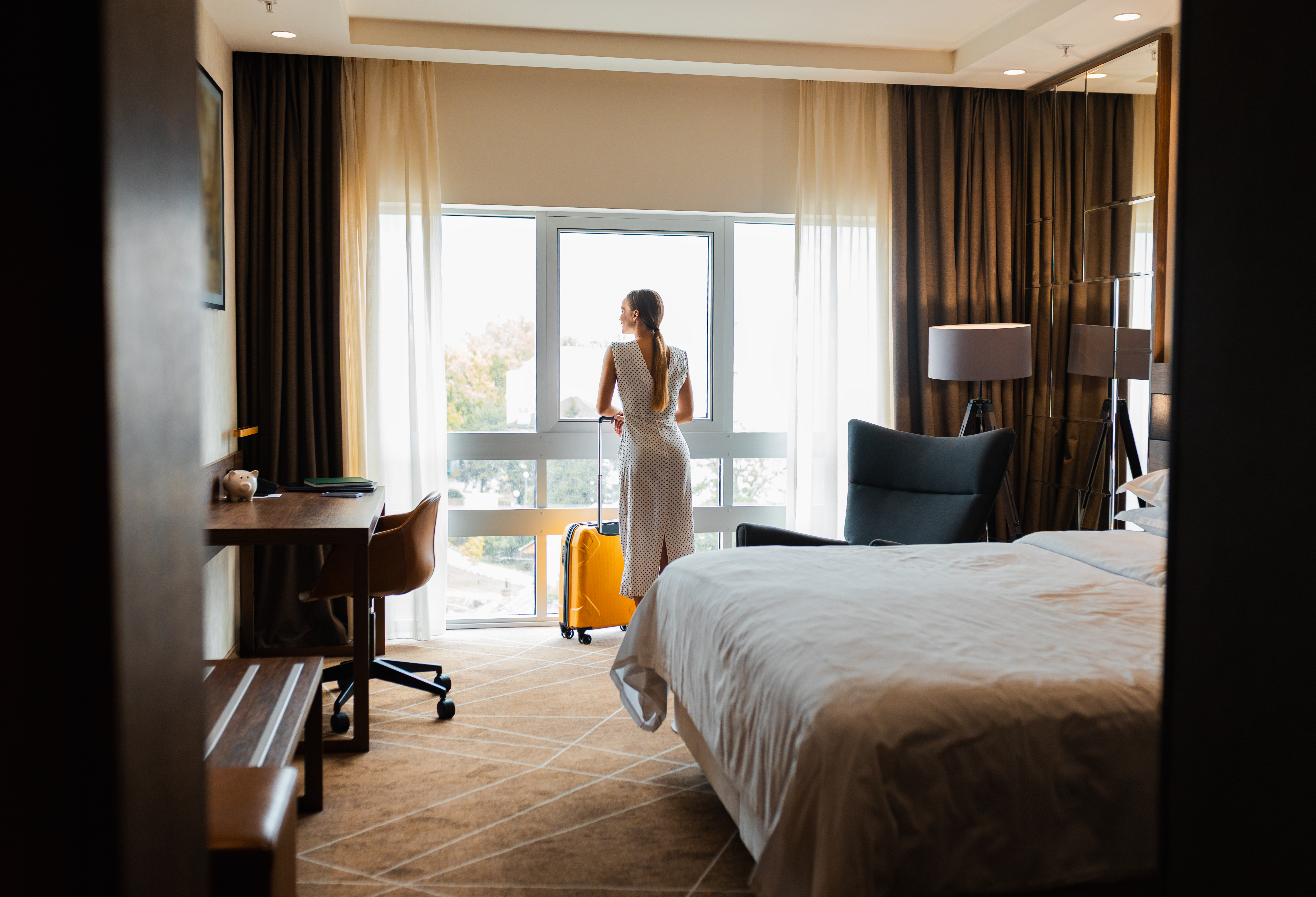 Rest Well, Roam Far: Why Handpicked Stays Elevate Your Multi‑Day Self‑Drive Tour 5 rear view of woman standing by window in hotel roo eb5b8c26238d0a0f26b3 BTOURS