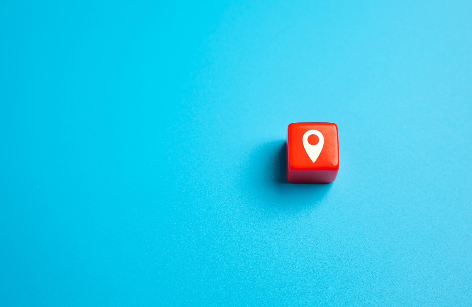 Red block with geolocation symbol on a blue background, representing local SEO and Google Business Profile management.