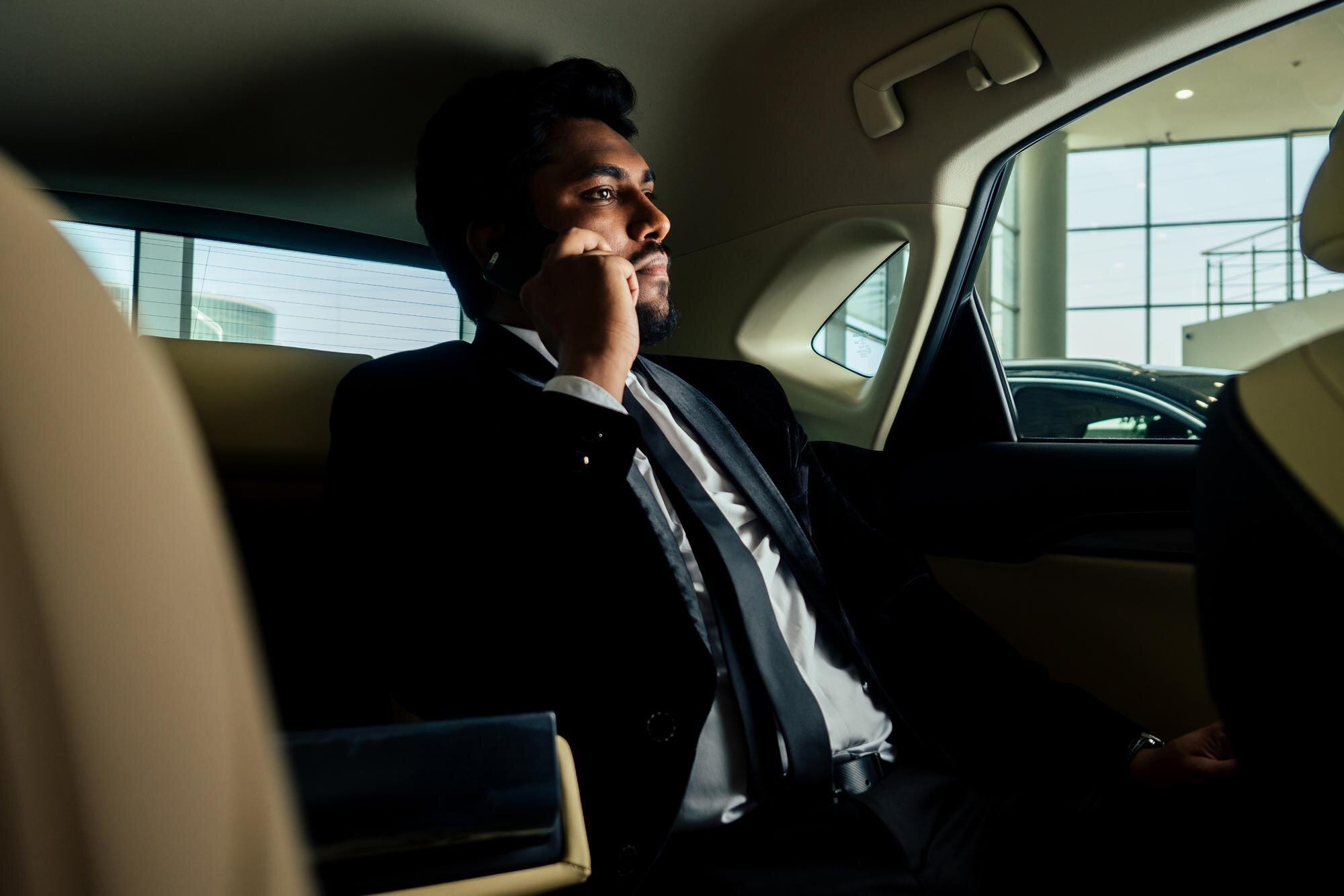 Executive passenger using a phone while enjoying a Luxury Limousine Service with Mak Louren.