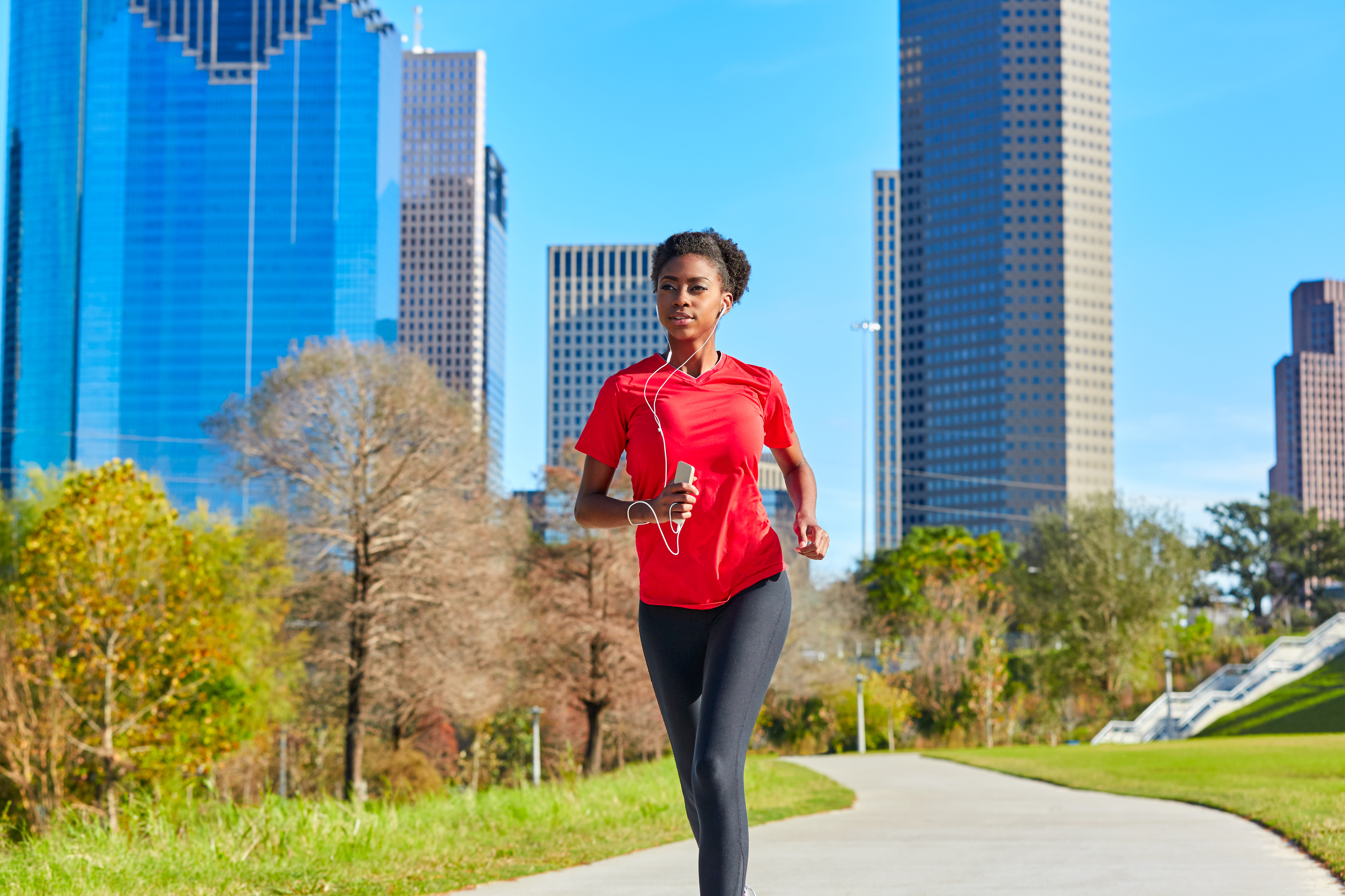 Young woman running along a path with earphones, fitting a run into her day