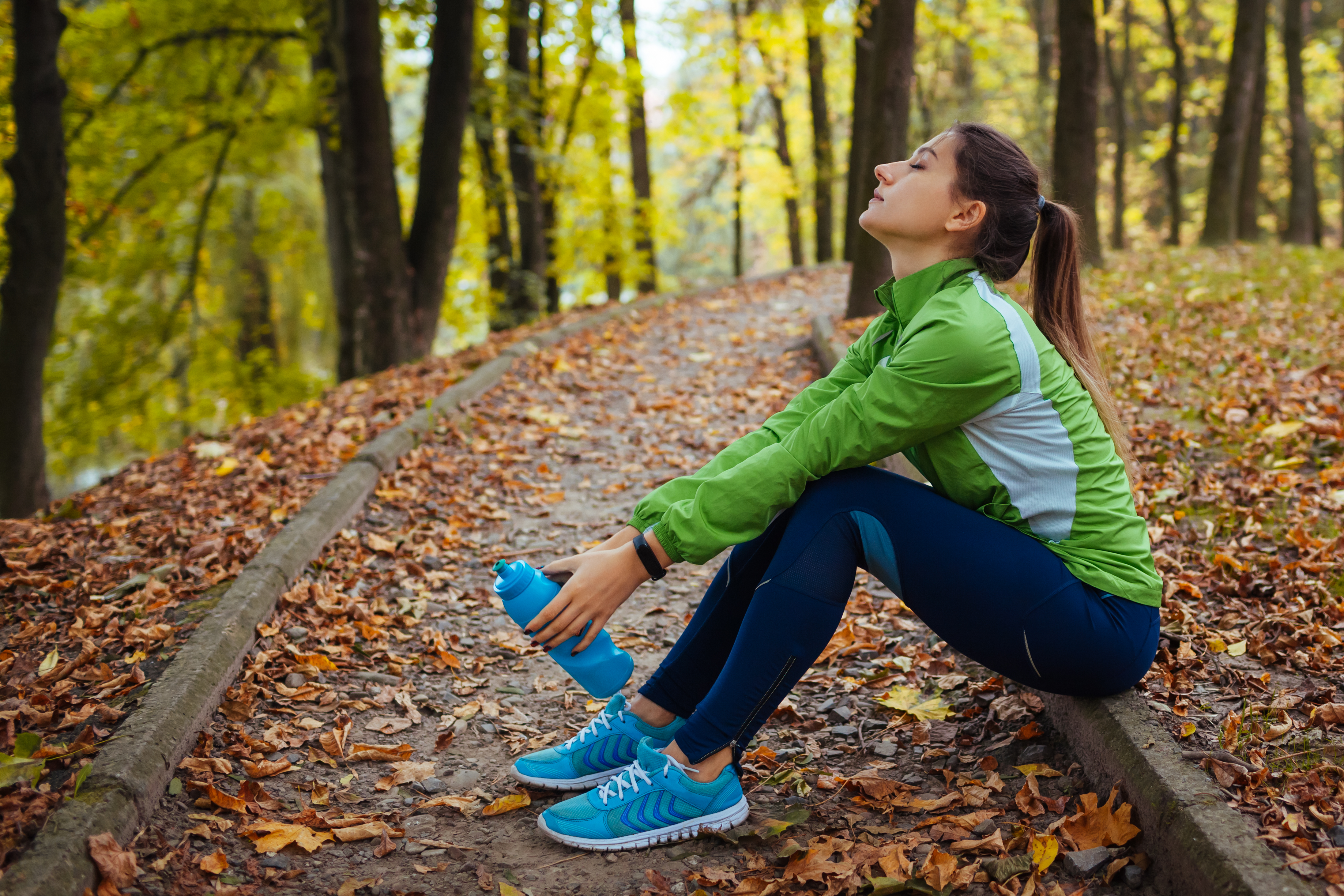 Tired runner resting on a bench in an autumn park after a hard workout