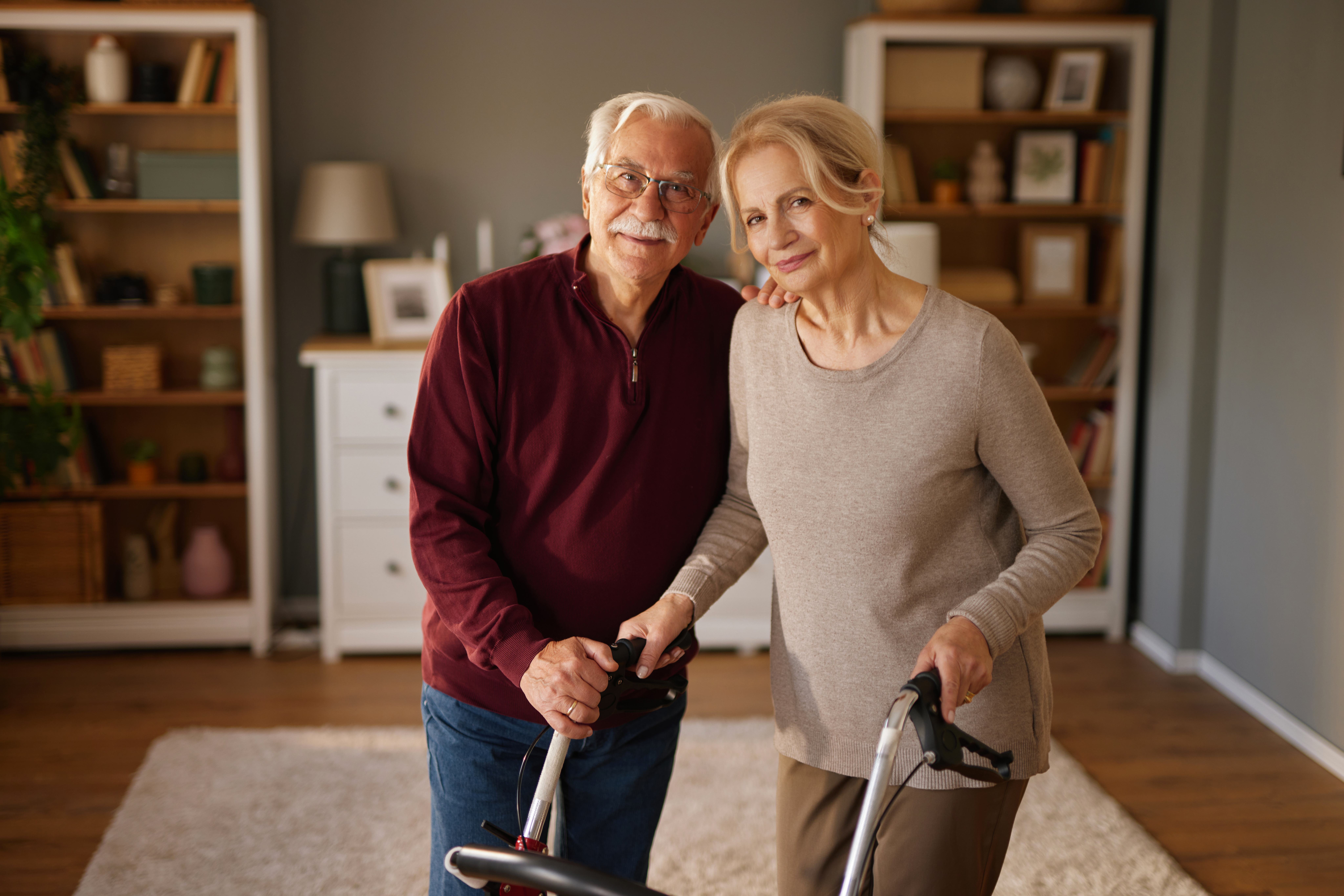 senior couple smiling and holding walking frame at d9e959cce3d7c3c1359e
