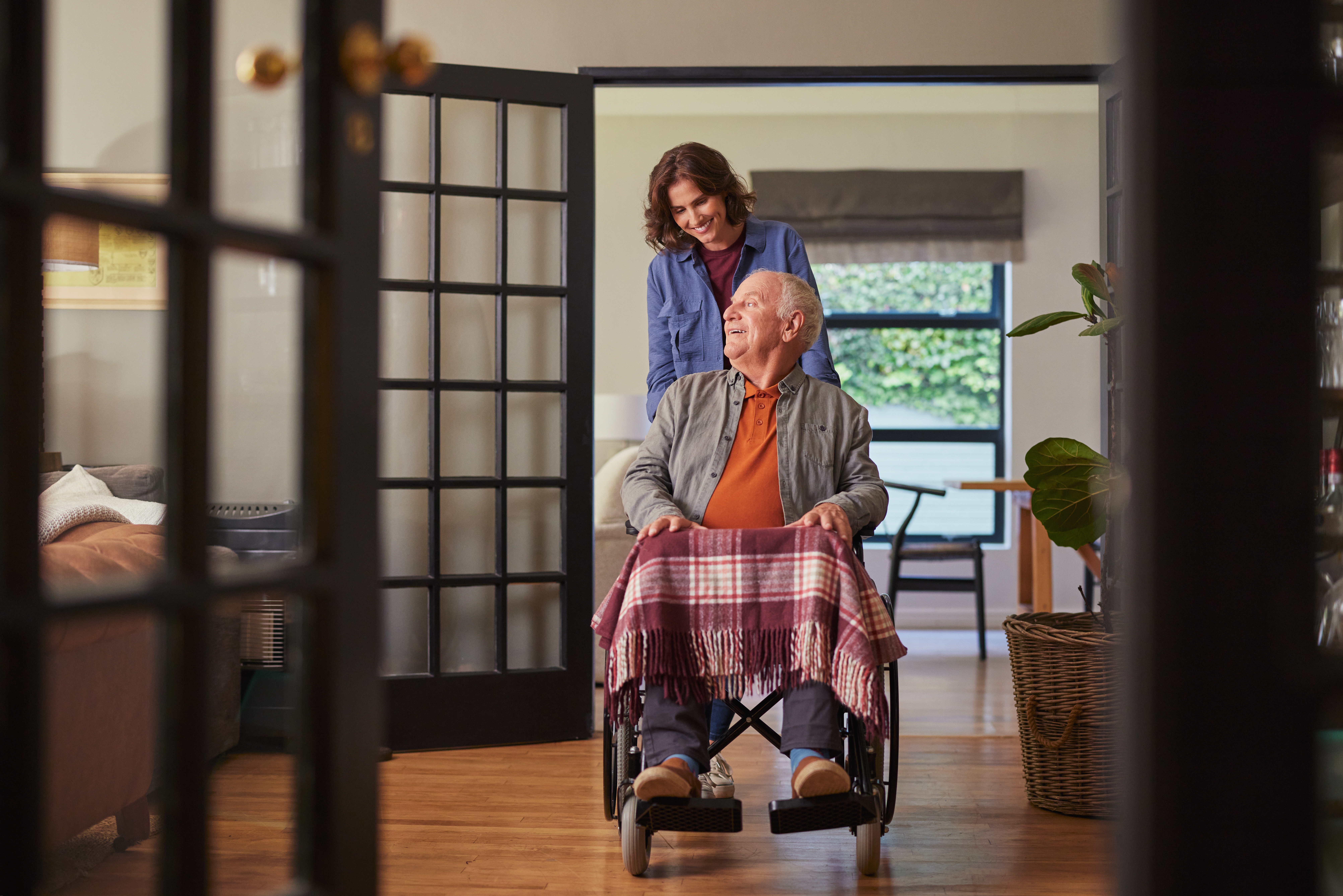 senior man in wheelchair pushed by smiling woman d7c29c6c2994ccef068e