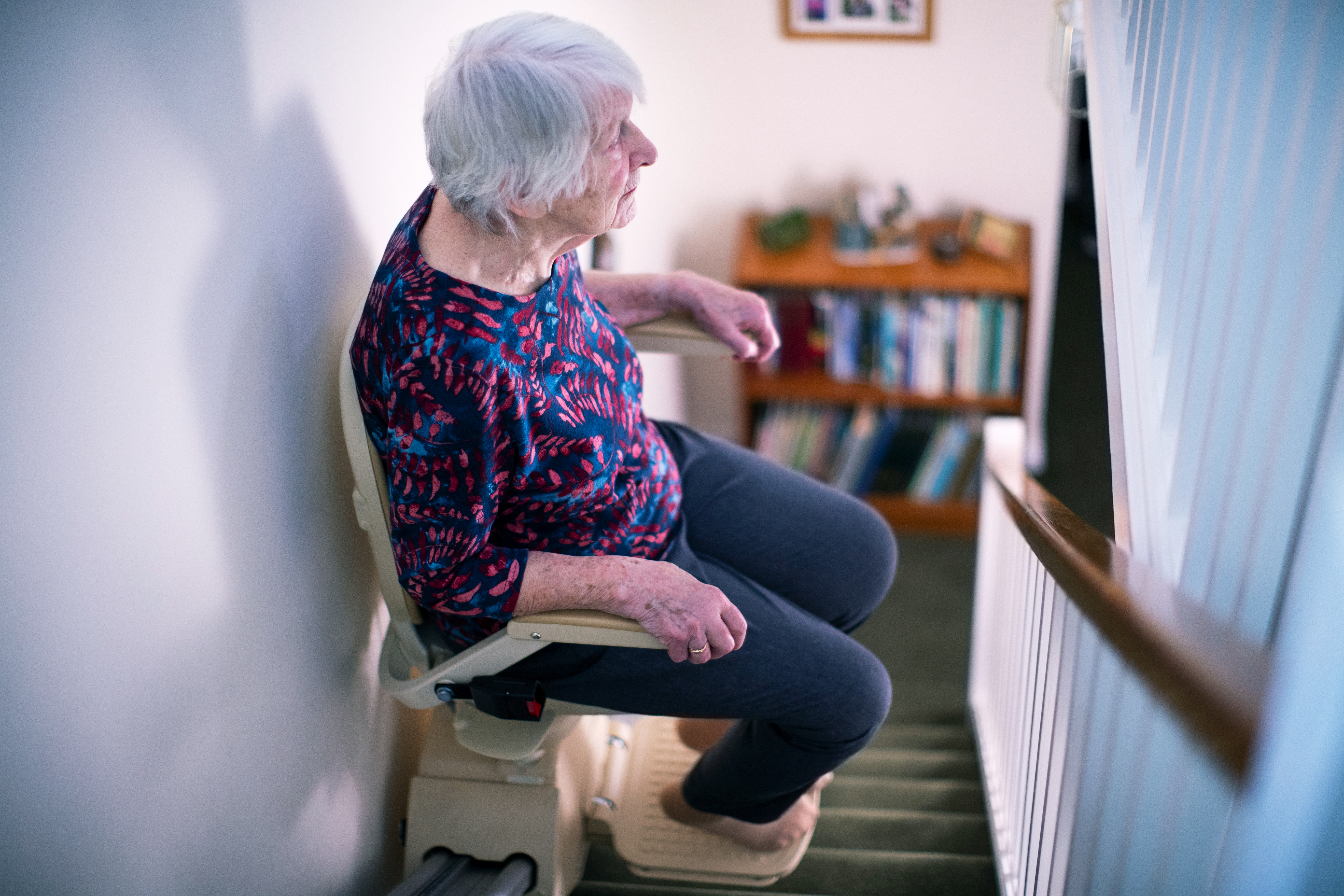 senior woman sitting on stair lift at home to help 7ab76767a5694d0103b8