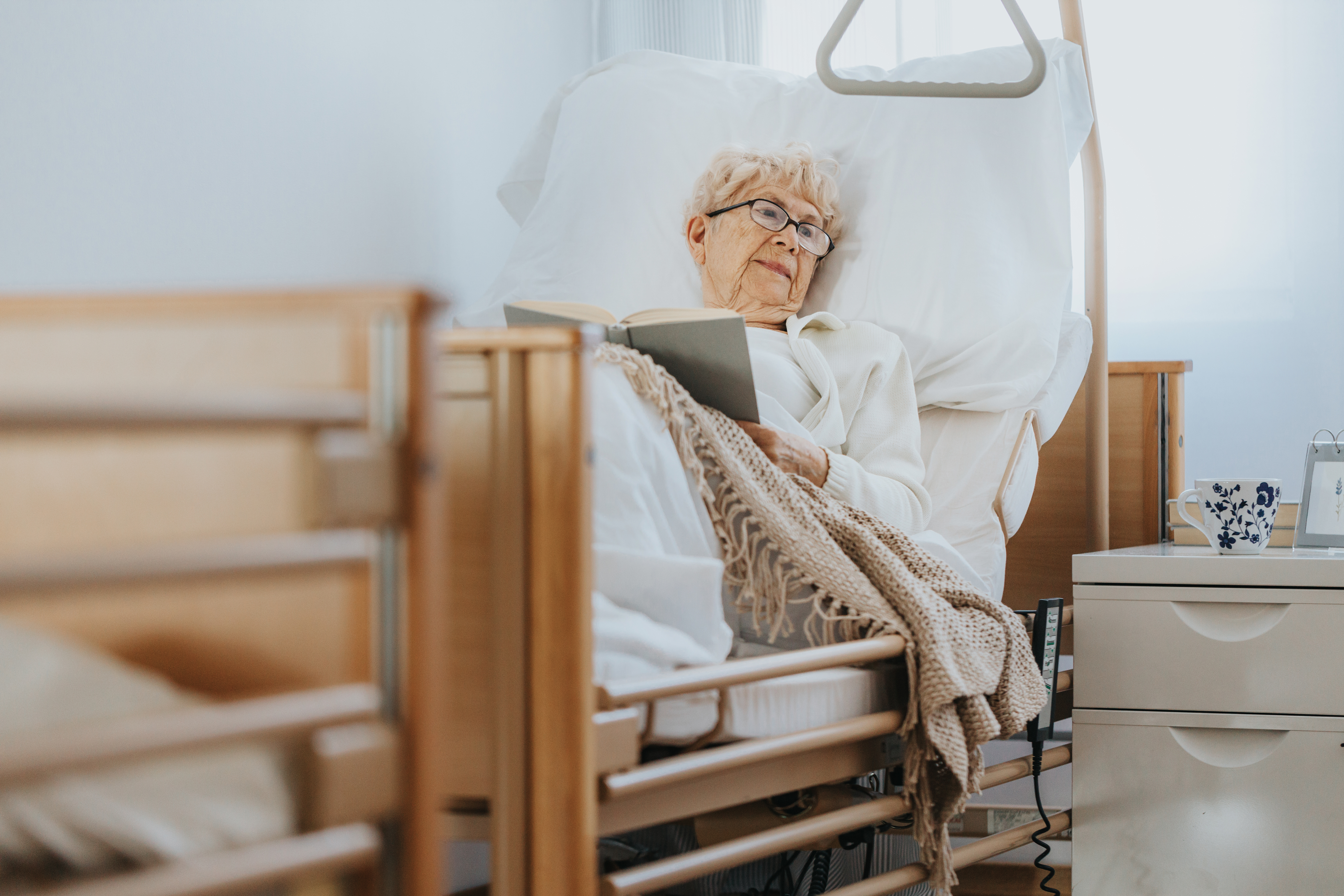 sick senior woman lies in a hospital bed and reads 46b82ff27379040ca88c