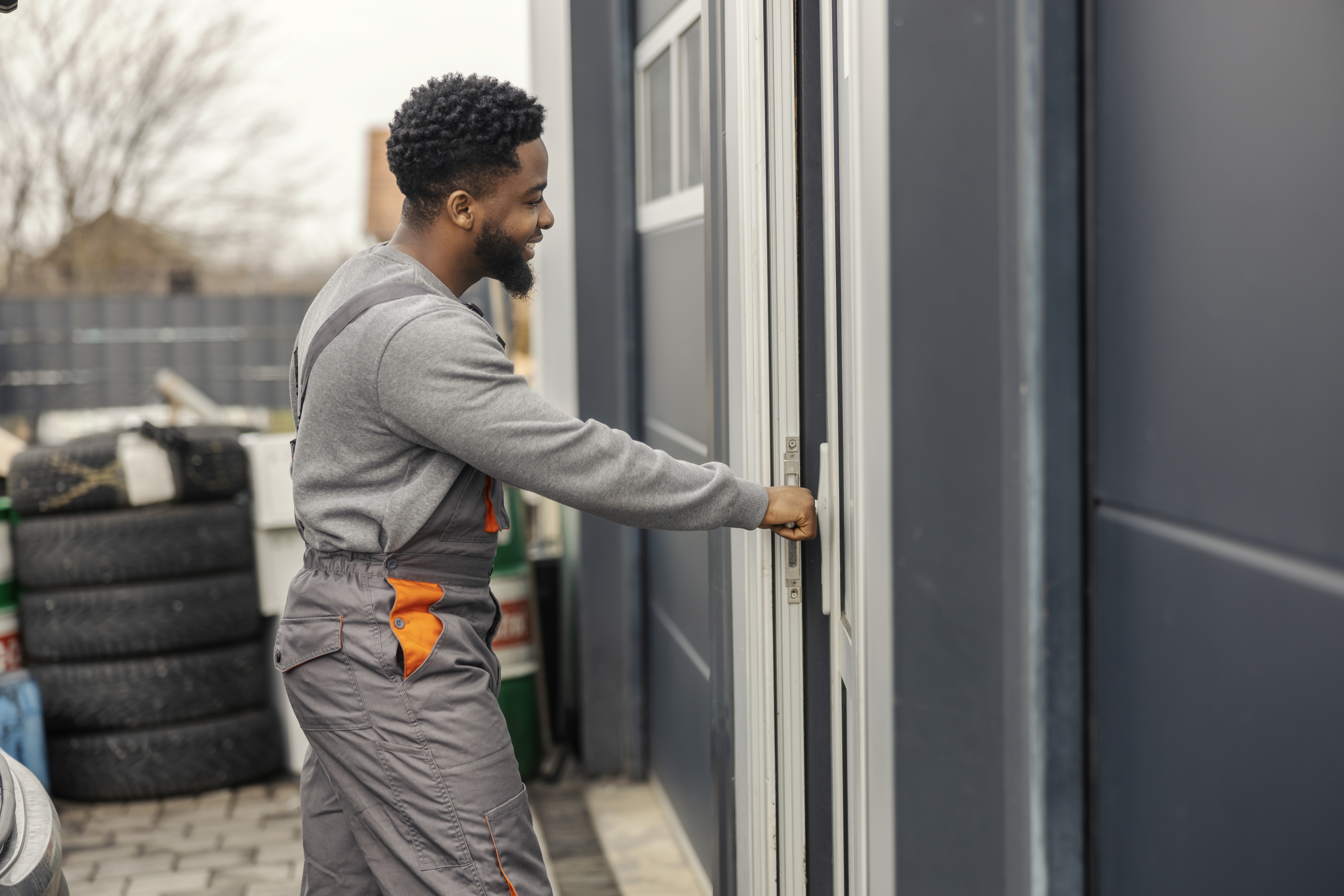 Unlocking Customer Happiness: How Same-Day Service Transforms Your Garage Door Experience 1 side view of black repairman in coveralls opening 84002dddc53a8c05c547