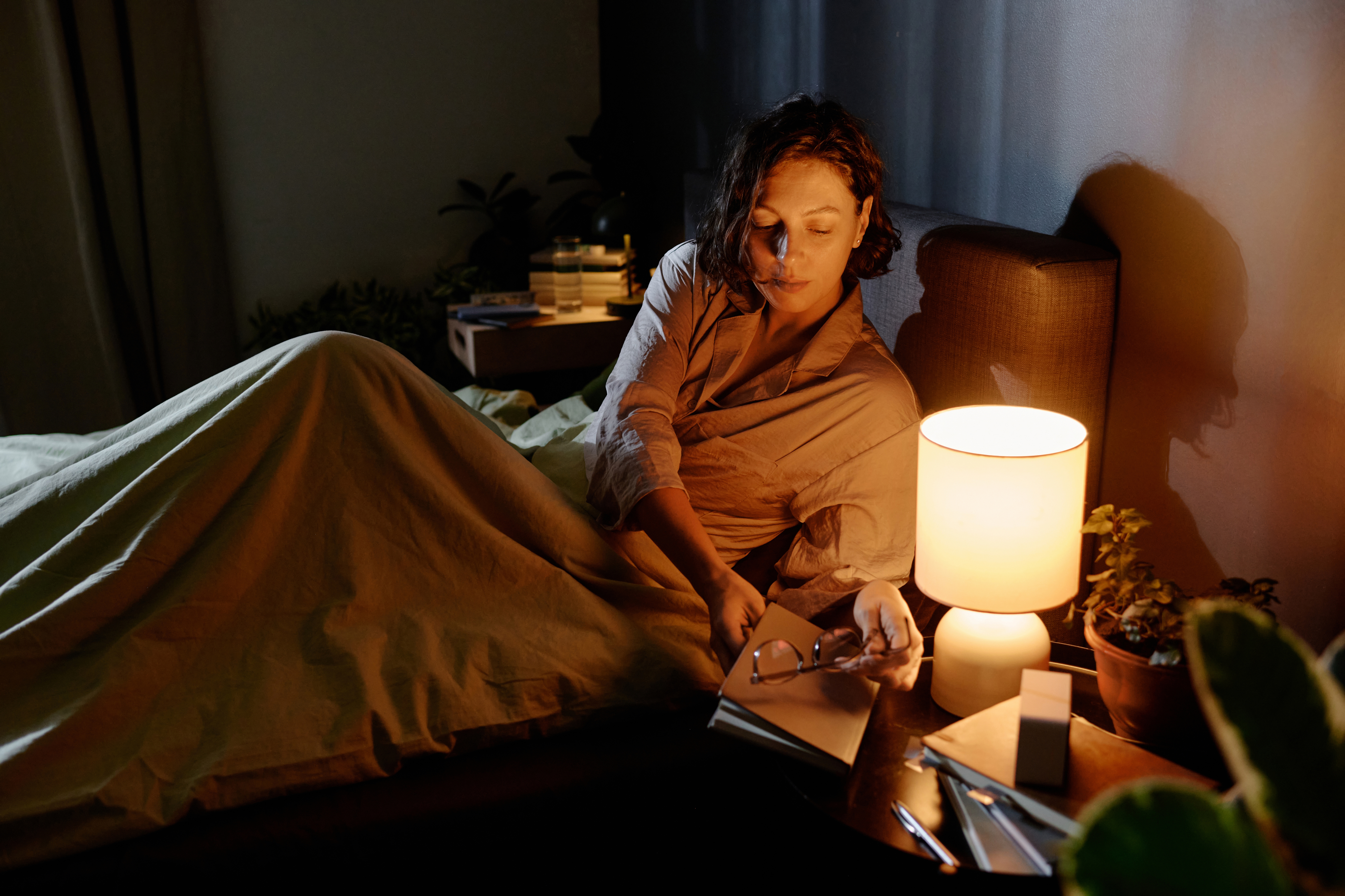 sleepy woman putting book down on nightstand 483c6a96e0cb82b7320d