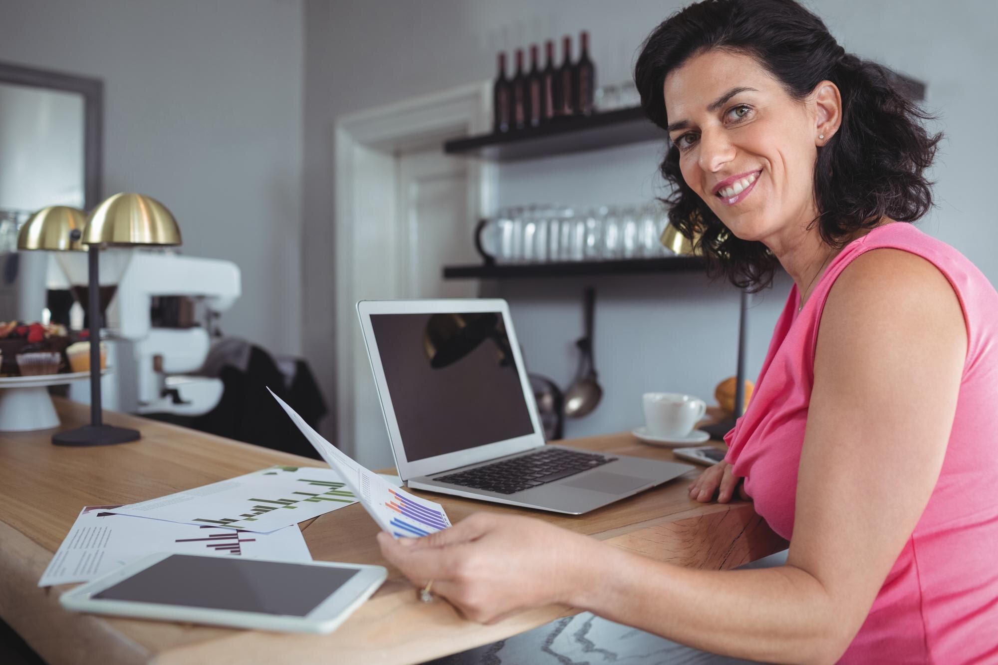 smiling businesswoman reviewing charts at modern c 714918dd625552e77734
