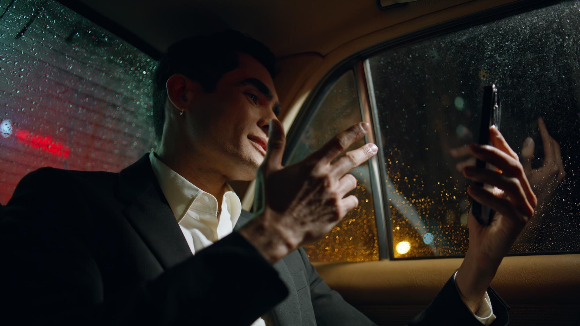 xecutive passenger using a smartphone in the back of a luxury vehicle provided by an hourly limo service during a rainy evening.