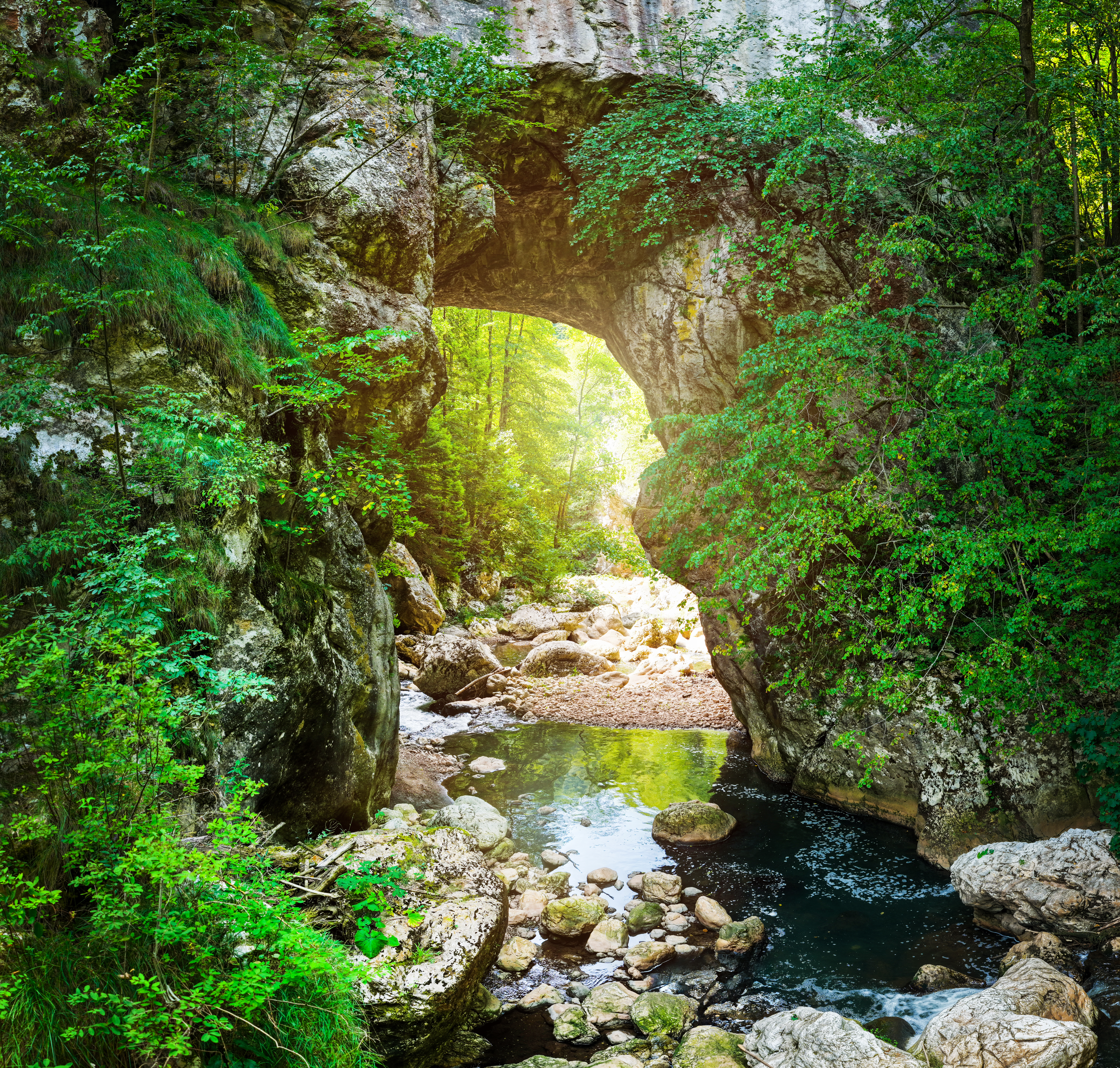 sunlit natural rock arch with a calm river and gre b40eb9cabfc93df67b93 BTOURS