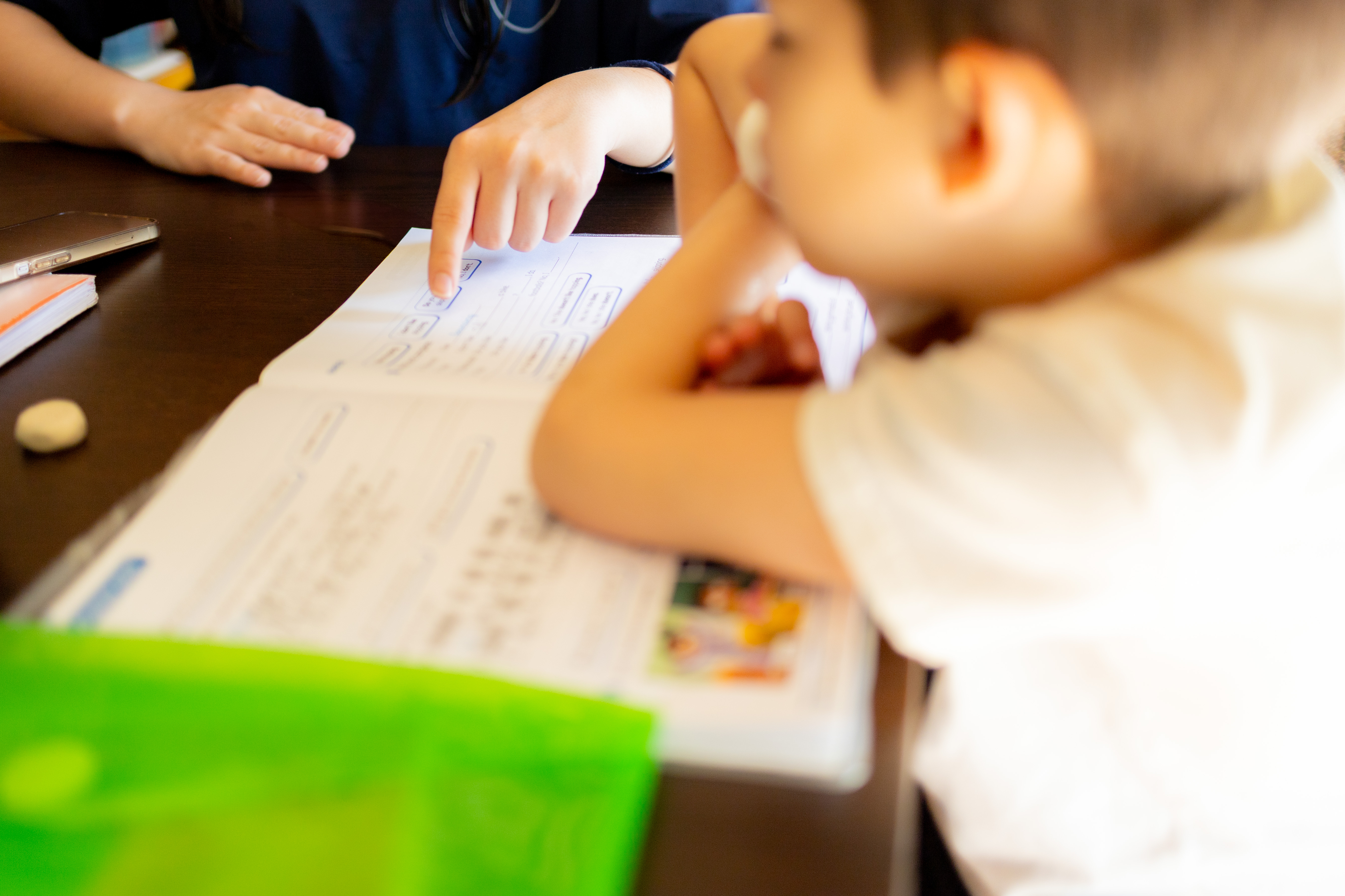 Teacher Helping Young Child With Reading And Writi 767093eb5c3eb25f5332