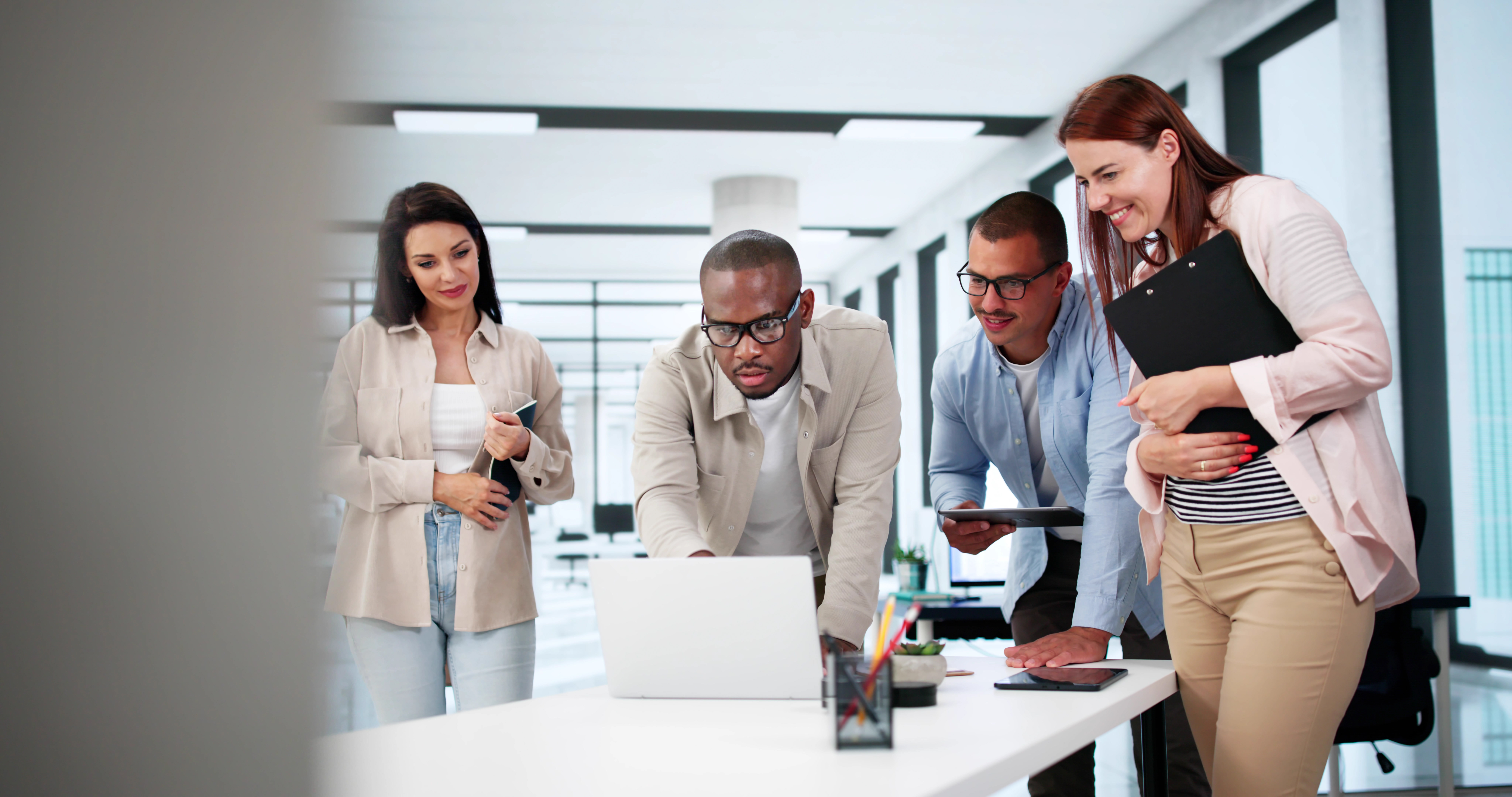 Group of diverse professionals collaborating in a modern office, focusing on a laptop, discussing strategies for online reputation management and review optimisation.