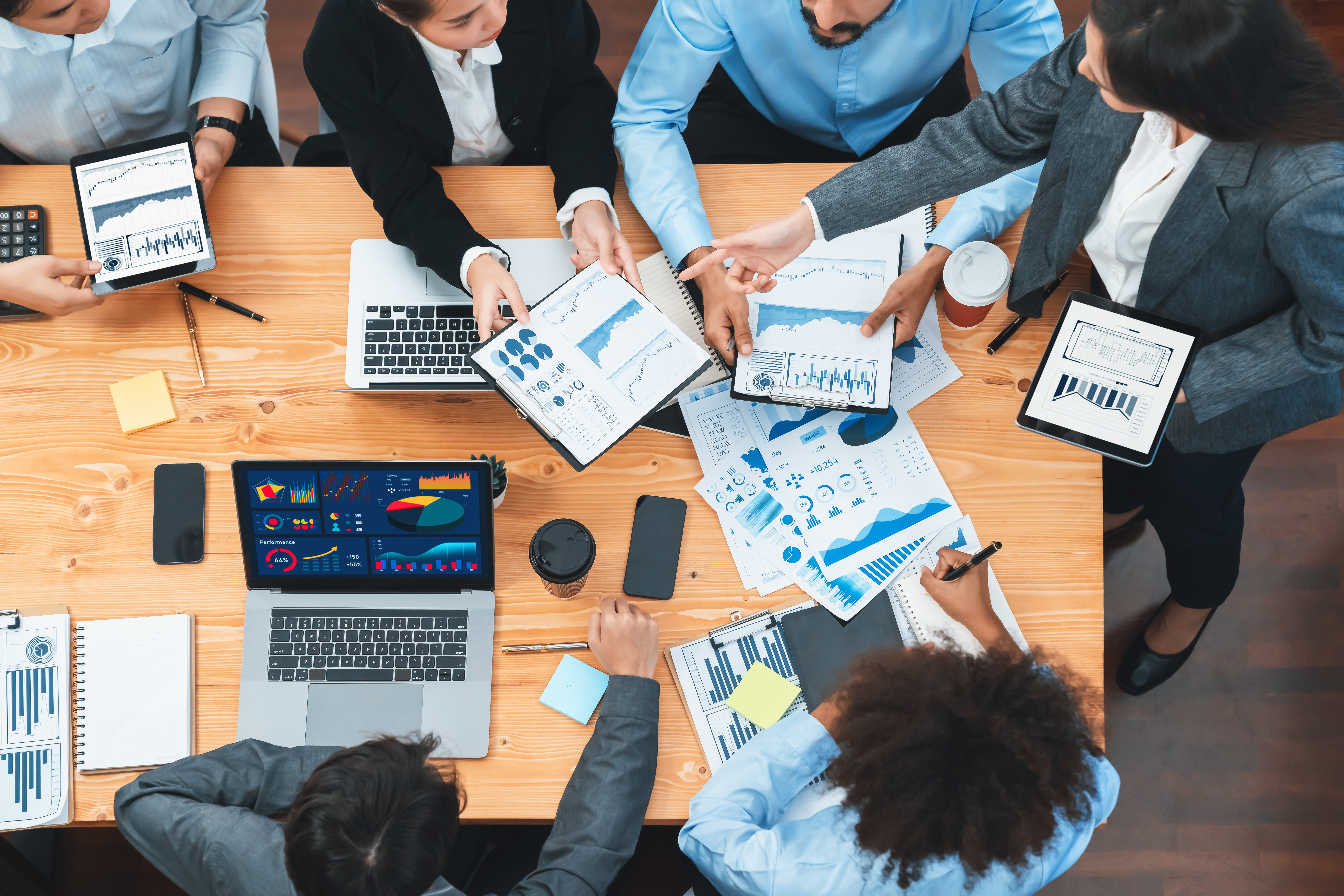 A top-down view of a business meeting focusing on data analysis, showcasing John Corner Web Design's solutions.