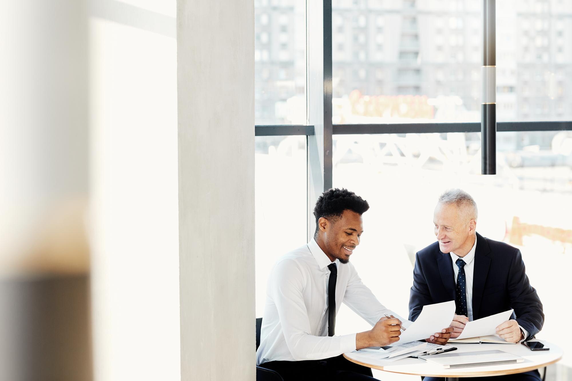 Two professionals discussing business papers at a table, showcasing collaboration and legal guidance for small business growth.