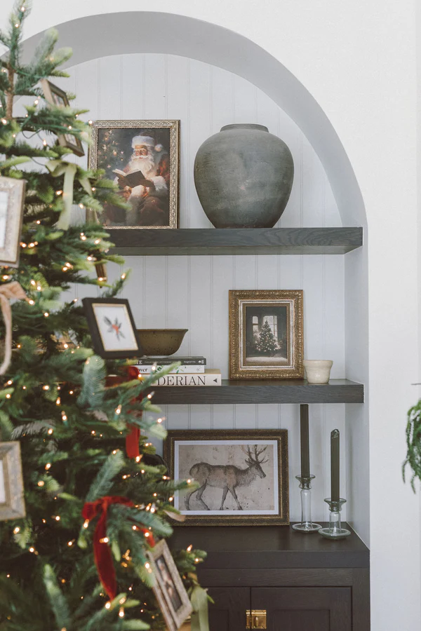 A holiday bookcase styled with art prints of a Christmas tree and a reindeer.