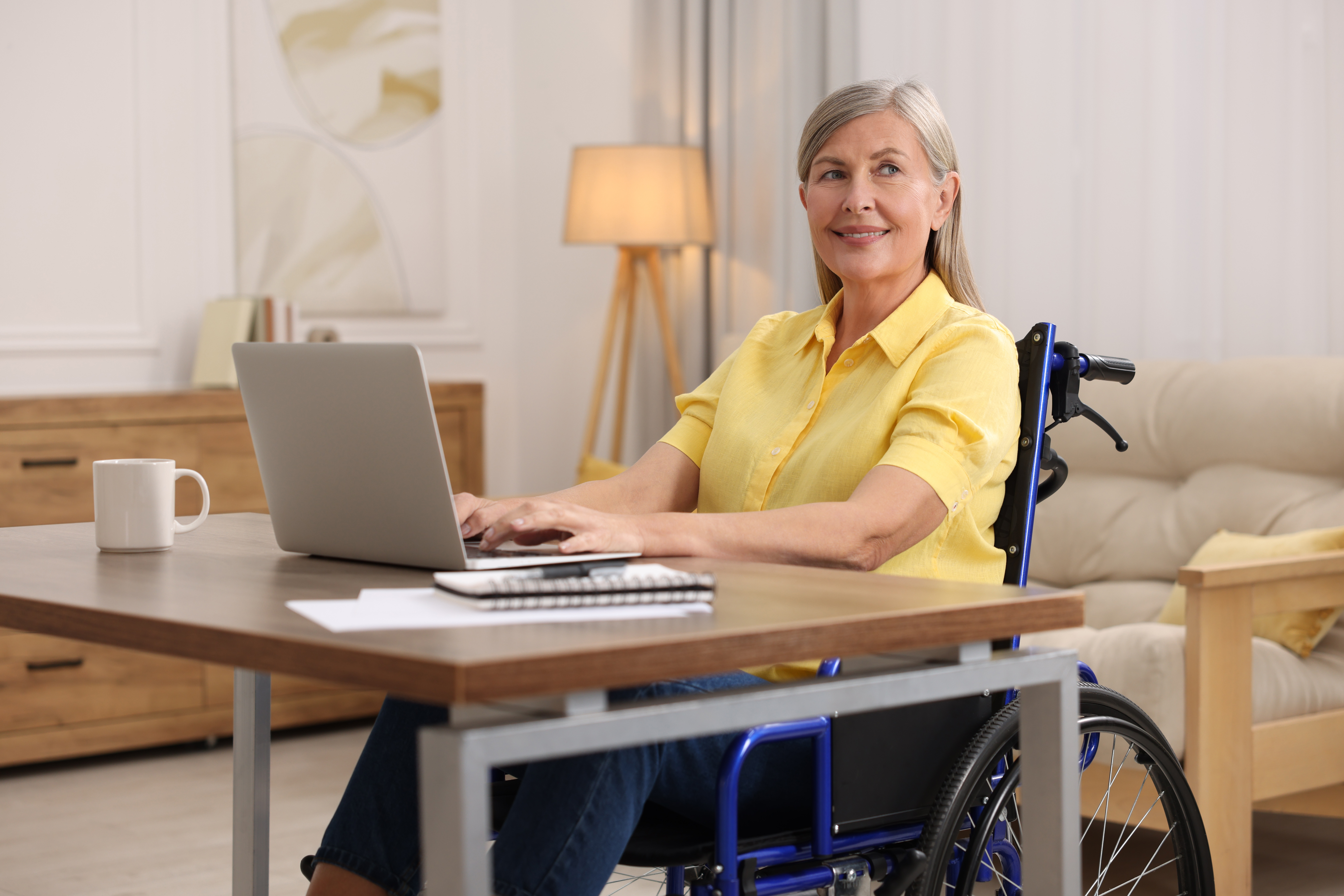 woman in wheelchair using laptop at table in home 70fc329c0c0e6e8eddeb