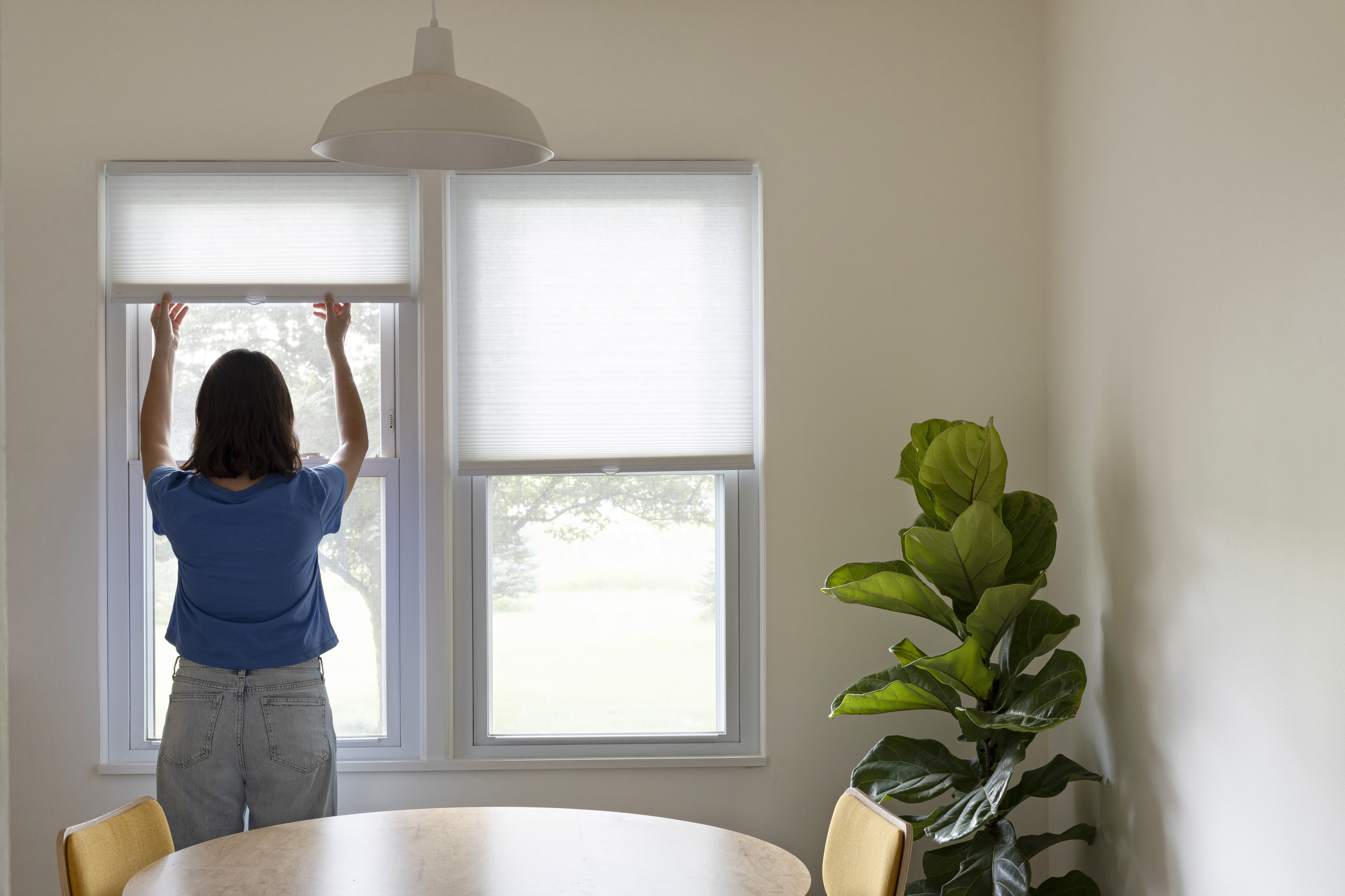 woman opening cellular shades in the dining room 67dbe31688112b38dbbd