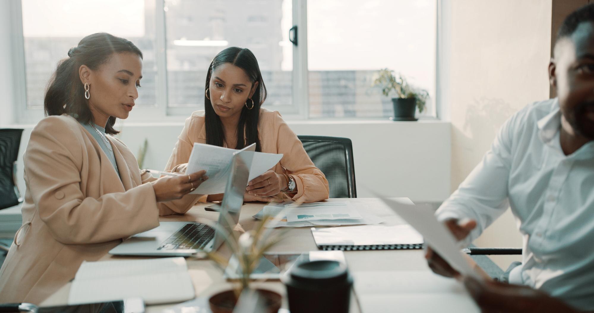 Women reviewing documents in a meeting, emphasizing contract discussions and collaboration in a business setting.