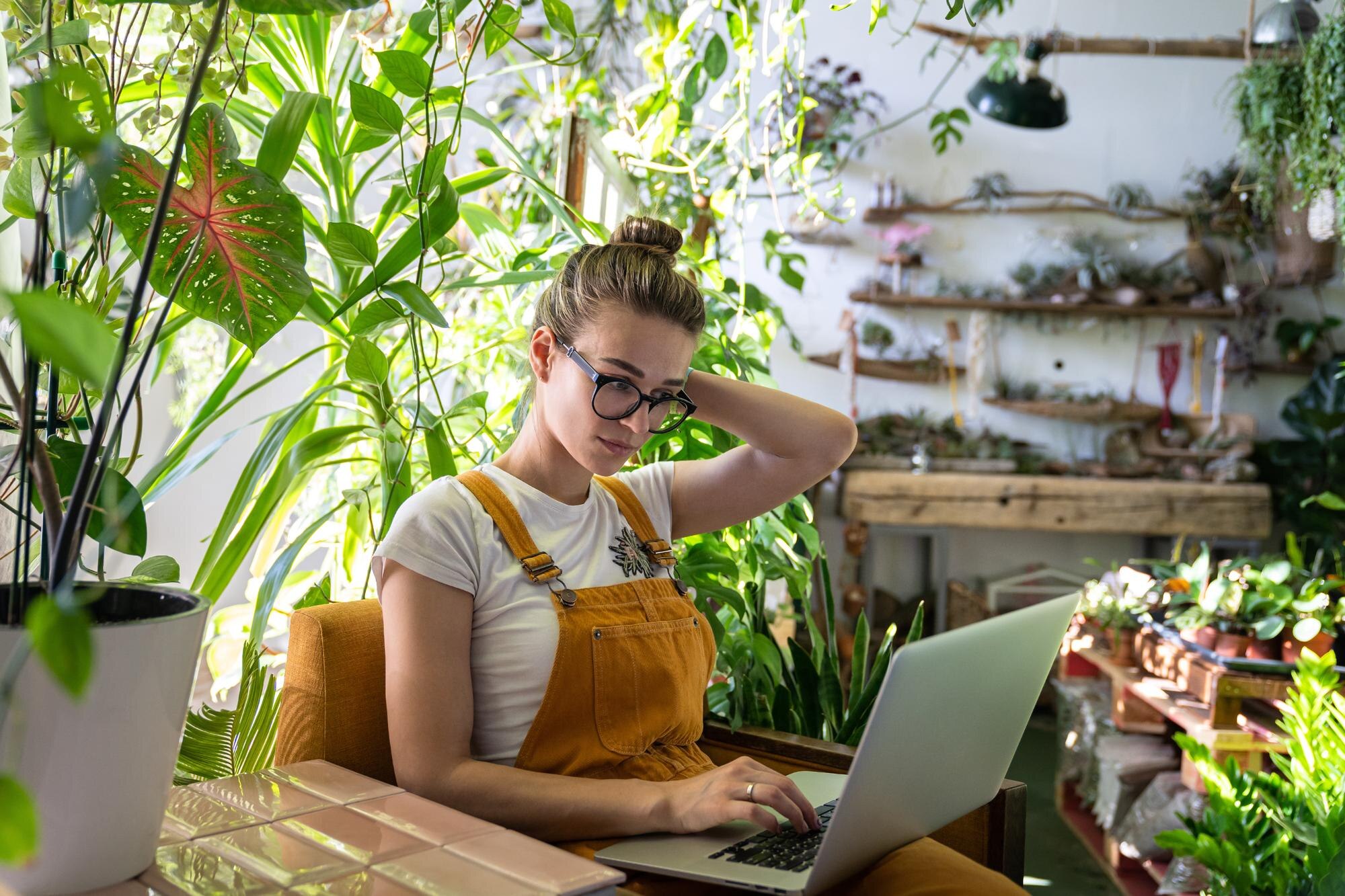 woman using laptop while sitting amidst plants in 333c83dfc99c80d6c930