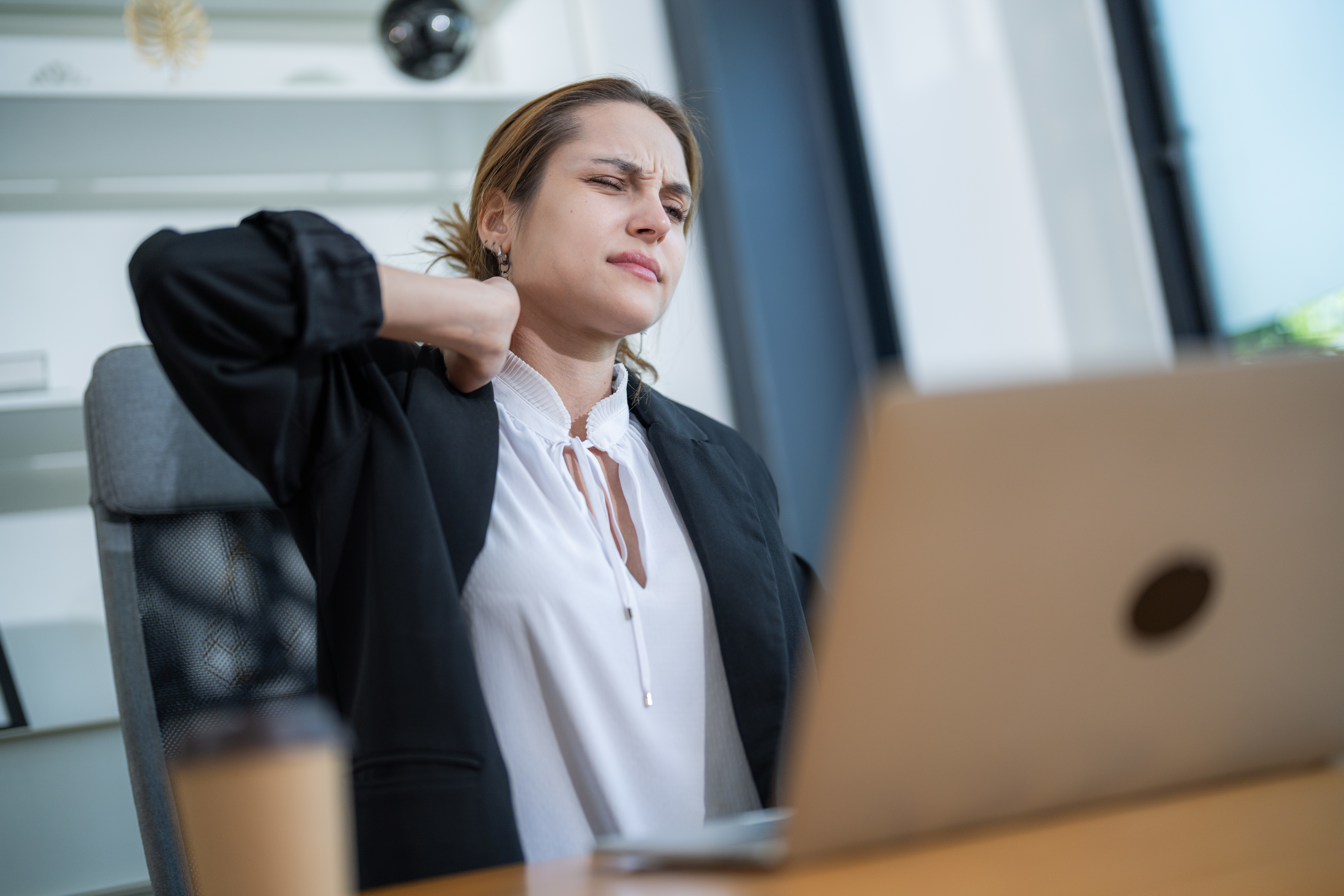 woman working at desk experiences neck pain while 7aa542ef5126c439d8b9