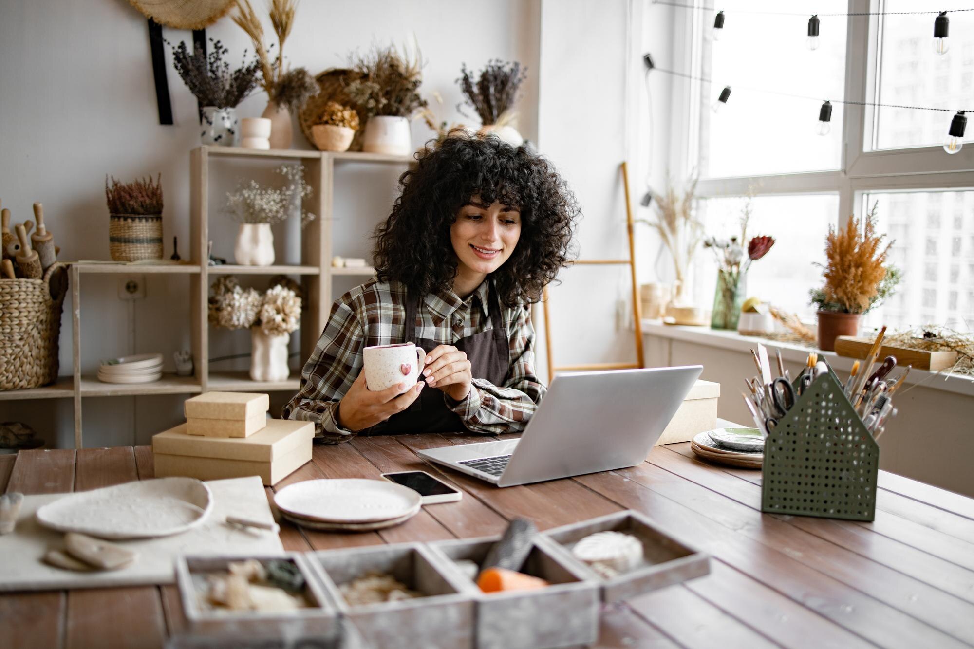 young ceramic shop owner using laptop while workin 1e1c564141fcee35bbbd