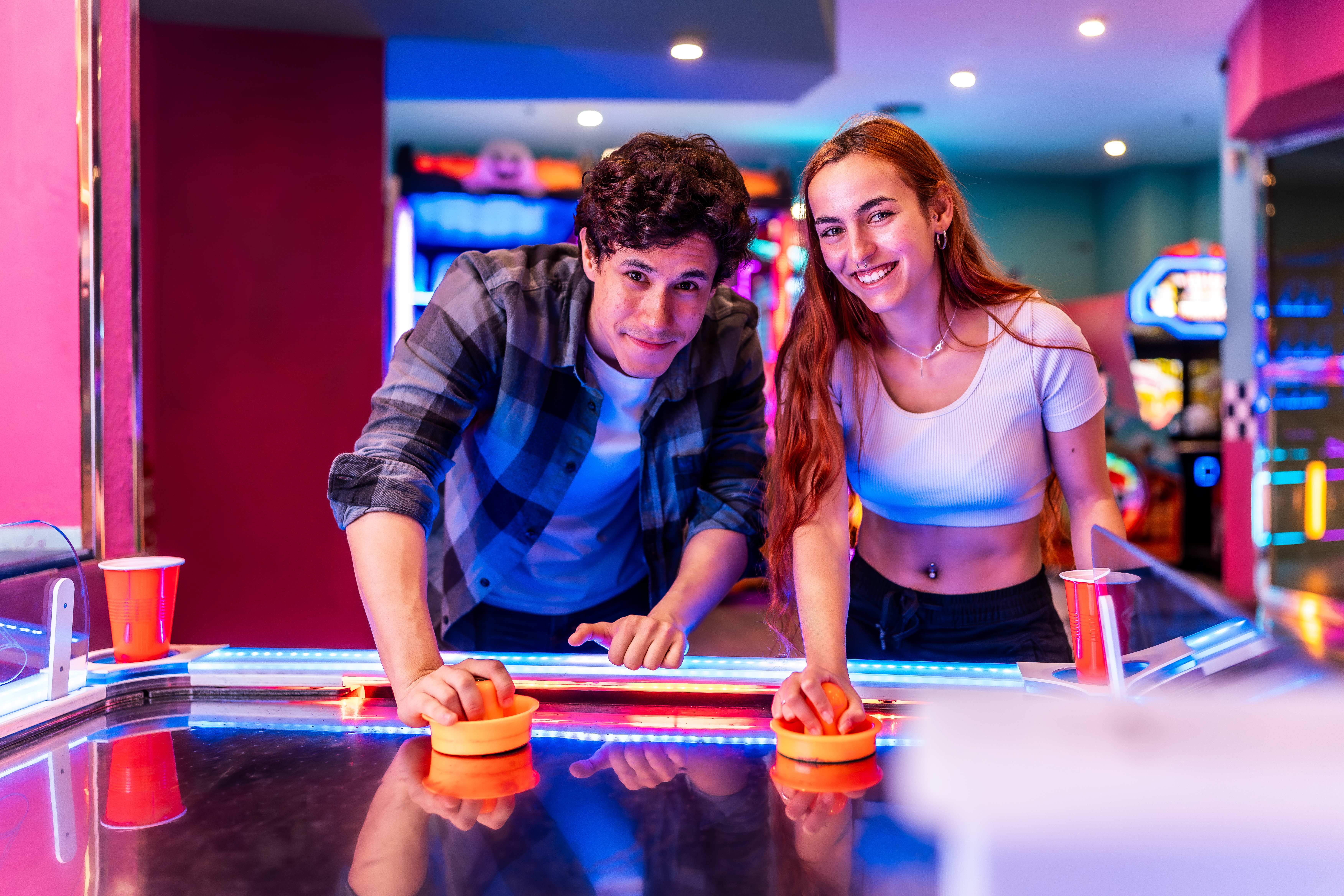 young couple playing air hockey in an amusement ar b0fc8da910d94ec1025f