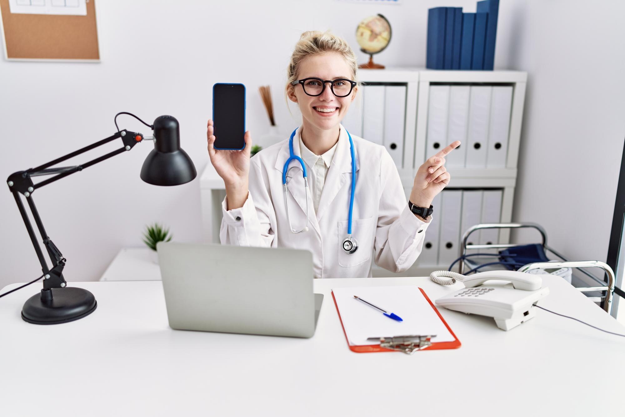 young doctor woman holding smartphone showing blan 6e0ca9ce2b3df59d4d3a