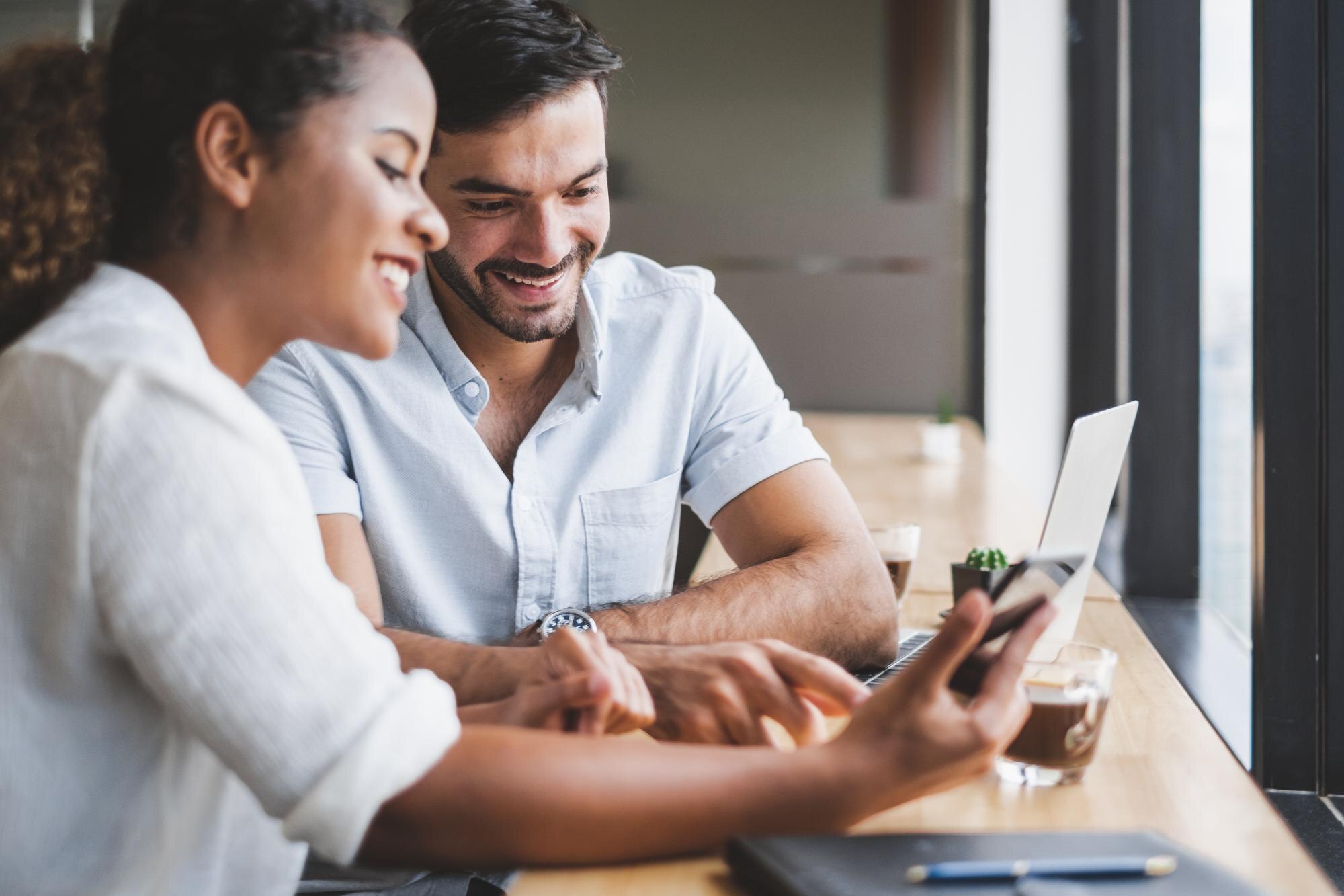 Young man and woman collaborating on a laptop in a modern workspace, discussing digital strategies for optimising Google Business Profiles.