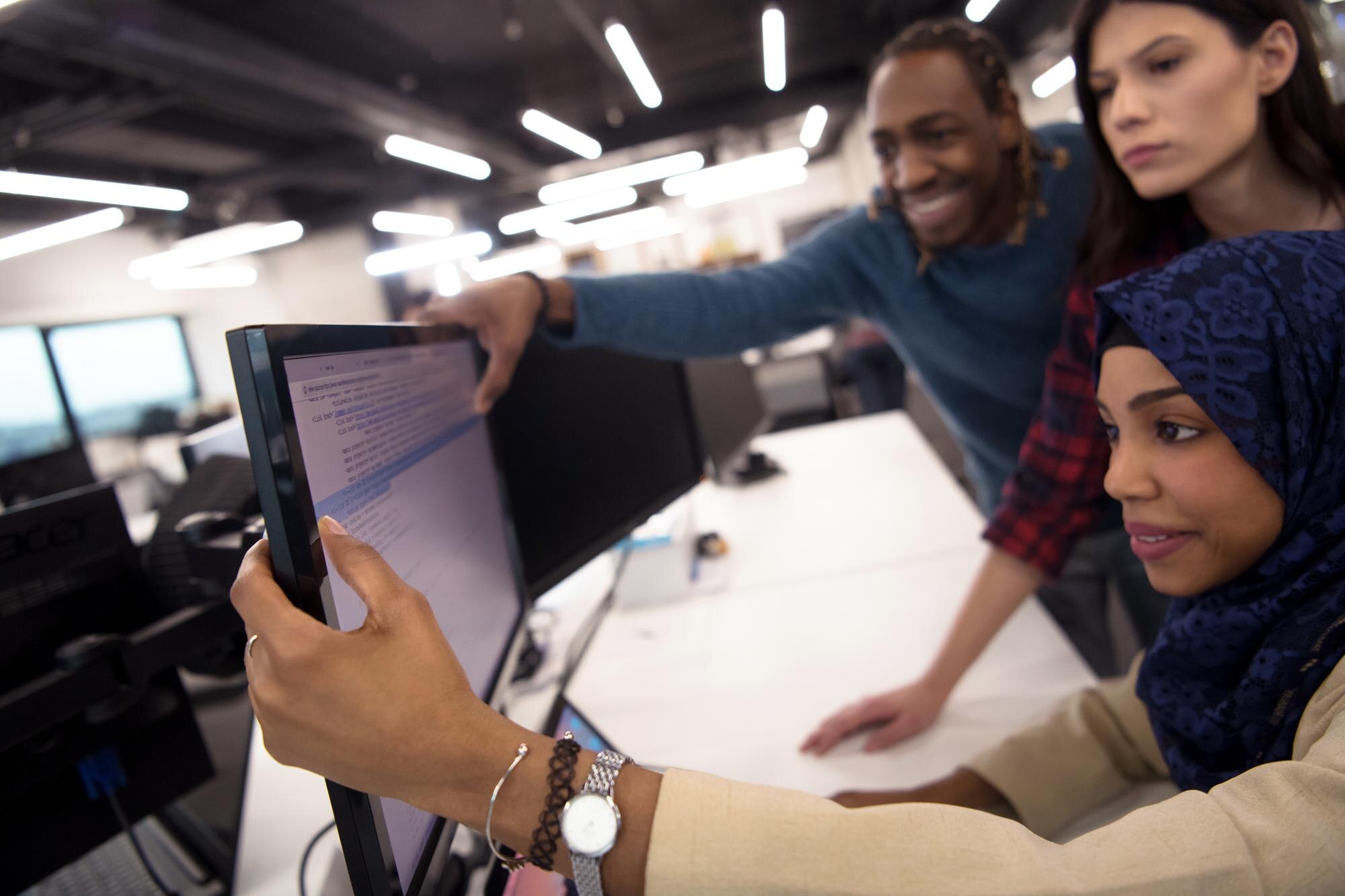 Young multi-ethnic business team collaborating around a computer, focusing on software development and Google Business Profile management.