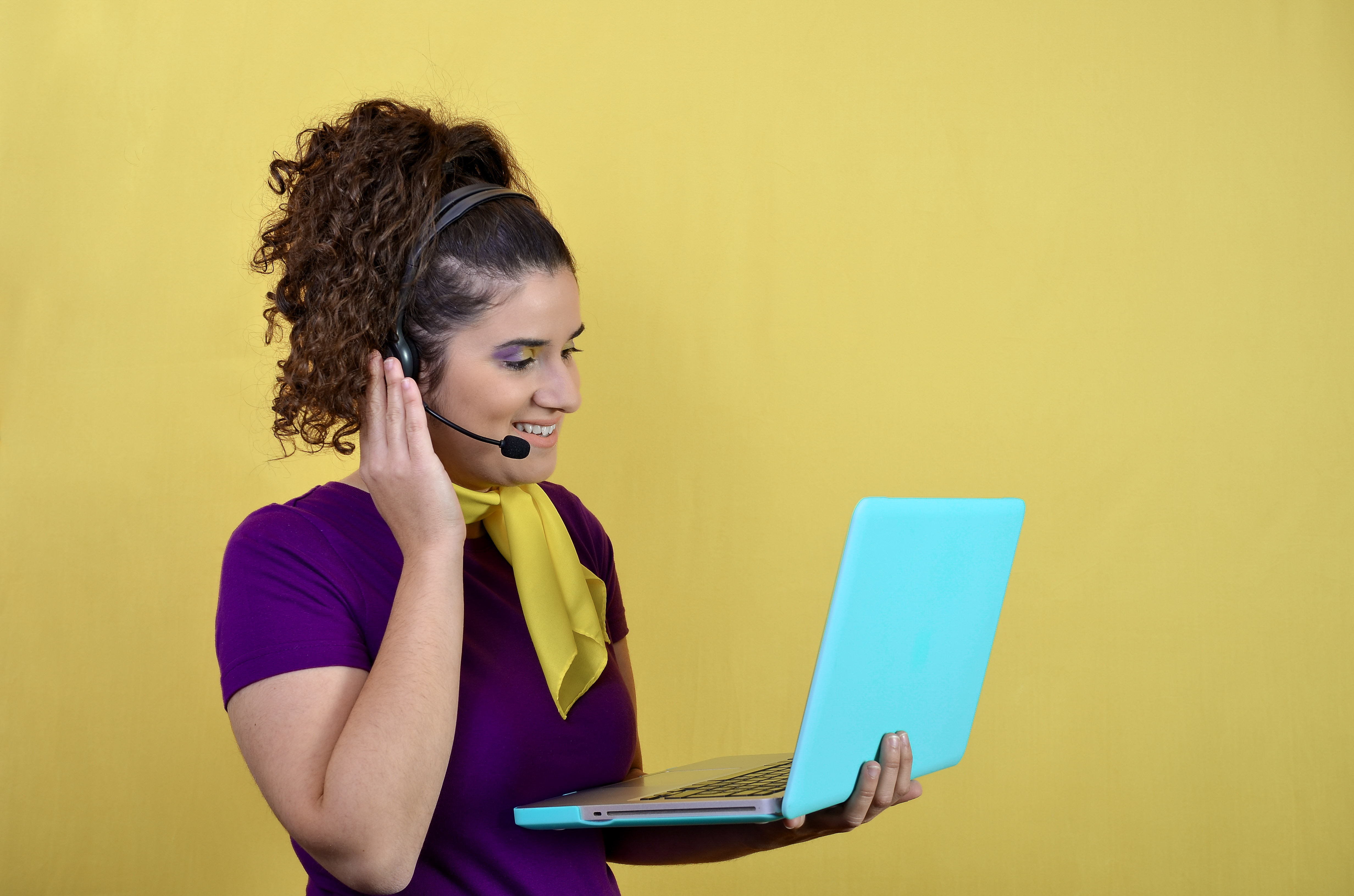 young woman with headset using laptop on yellow ba 3b3137f3046754f52d78
